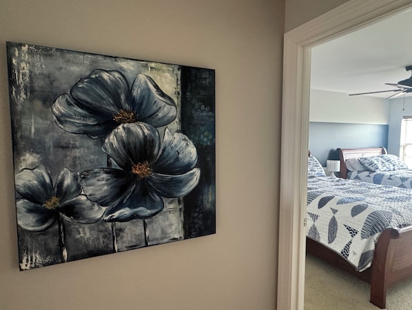 A bedroom with a bed, a nightstand, and a wall-mounted painting.