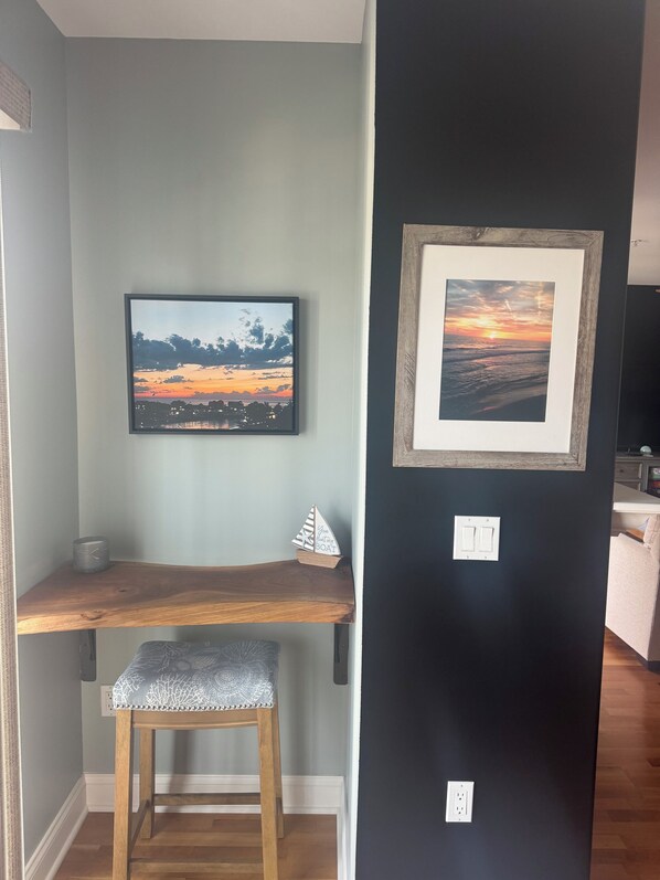 A room with a desk, a chair, a framed picture on the wall, and a small decorative boat.