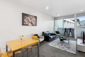 Ein modernes Wohnzimmer mit Esstisch, Sofa und Couchtisch.