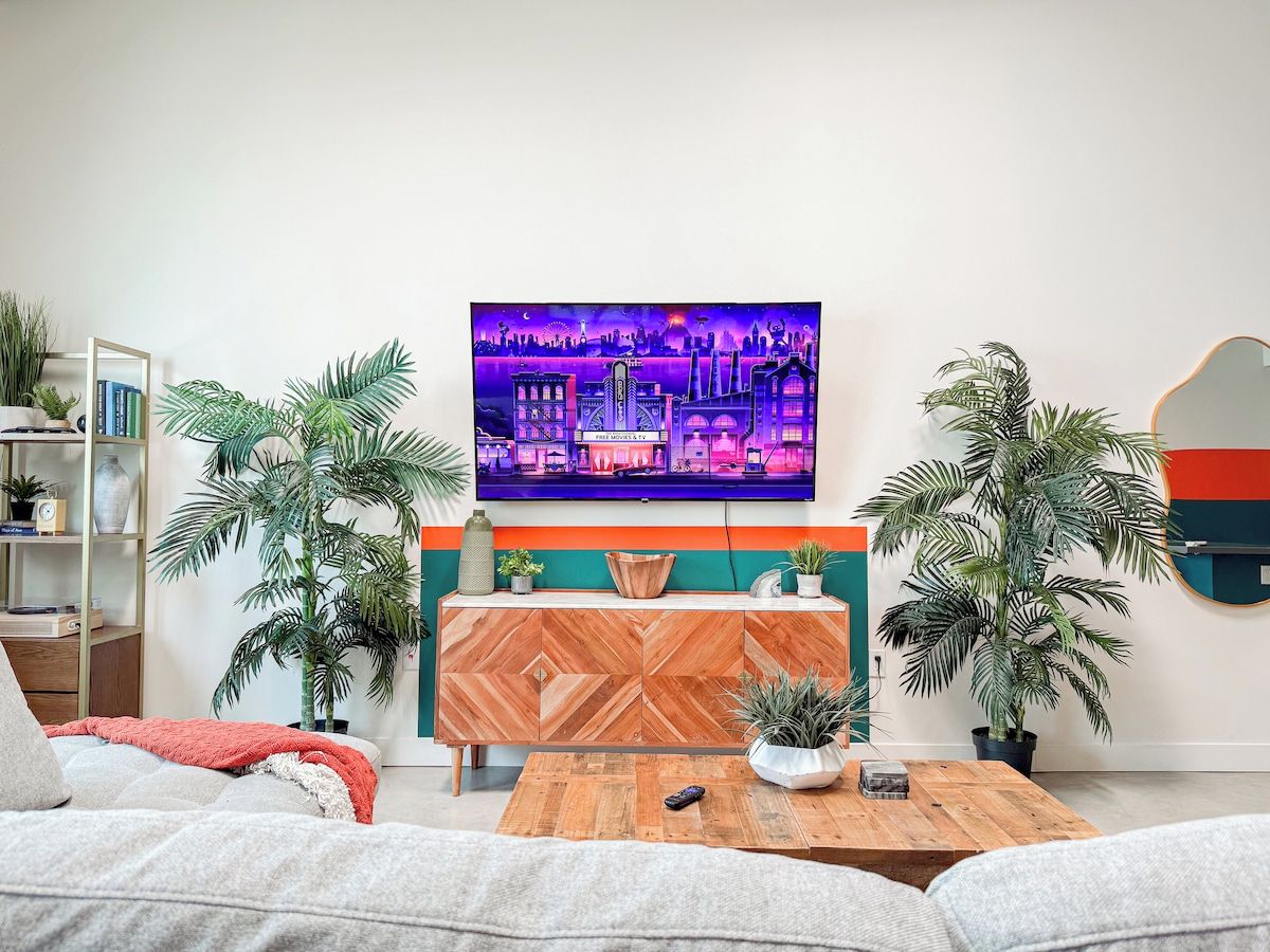 A living room with a sofa, coffee table, and a TV mounted on the wall.