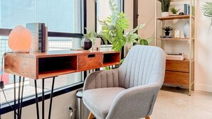 Een moderne kamer met een bureau, stoel, boekenplank en grote ramen.