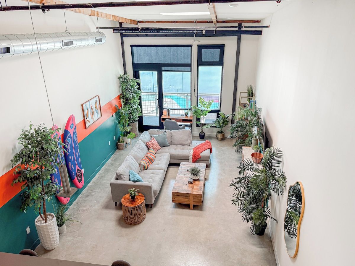 Una sala moderna con un sofá seccional, una mesa de centro y varias plantas.