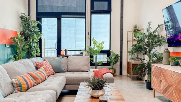 Een moderne woonkamer met een modulaire bank, een salontafel en diverse planten.
