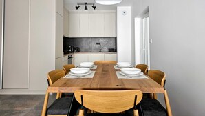 Un espace repas moderne avec une table en bois, six chaises et un luminaire suspendu.