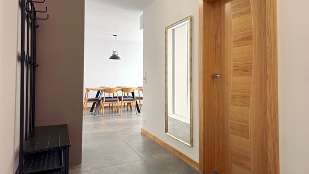 Un couloir avec une porte en bois, un coin repas avec une table et des chaises, et un luminaire suspendu.