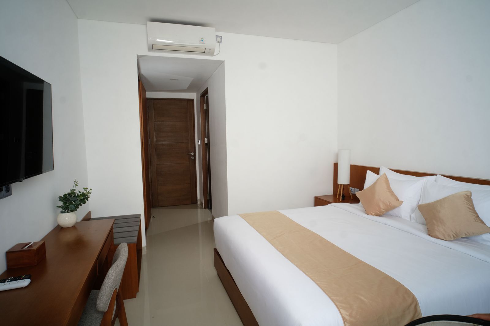 Une chambre d’hôtel équipée d’un lit, d’une table de chevet, d’une lampe, d’un téléviseur et d’un appareil de climatisation.