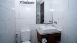 A bathroom with white tiles, a white toilet, a sink with a mirror, and a towel rack. - THE LEDGE ULUWATU (Pecatu)