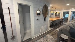 Um corredor com piso de madeira, uma sala de jantar com mesa e cadeiras de madeira, e uma sala de estar com um sofá.