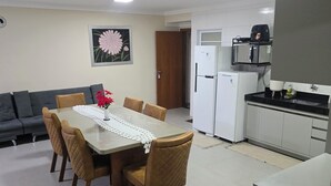 A compact living space with a dining area, kitchenette, and a door leading to another room. - Luxury apartment 200 meters from the beach. (Porto Seguro)