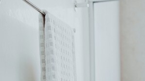 Une salle de bain avec une serviette suspendue à un porte-serviettes, un espace douche et des murs carrelés.