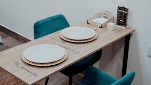 Une table à manger dressée avec des assiettes, des couverts et un présentoir à menus.