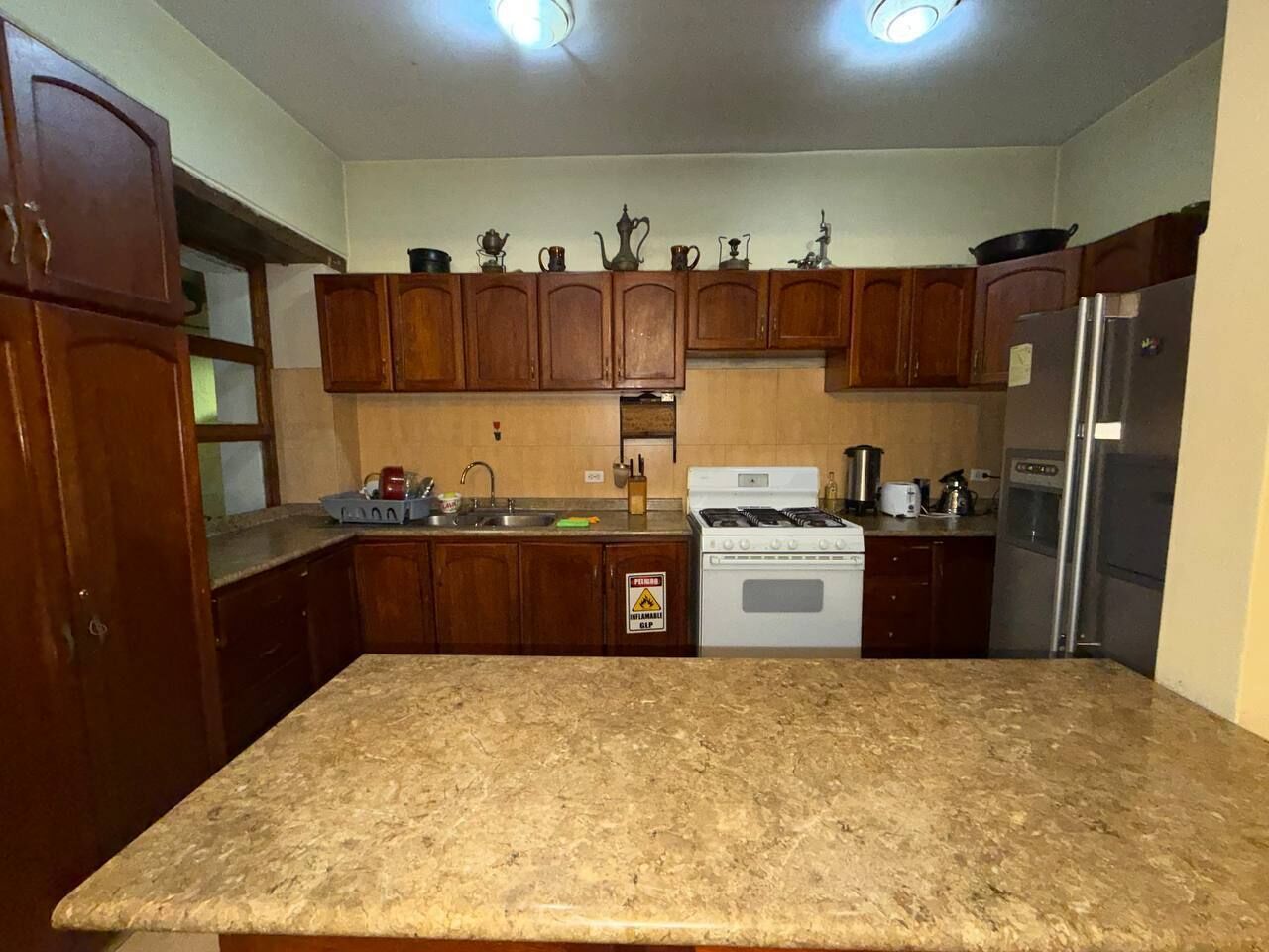 A kitchen with wooden cabinets, a granite countertop, a stove, and a refrigerator.