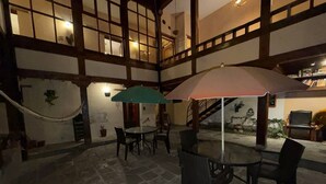 An indoor patio with stone flooring, wooden beams, and tables with chairs. - Hotel Casa Olmedo (Quito)