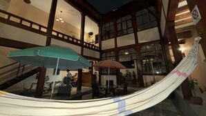 A spacious indoor area with a hammock, two umbrellas, and a staircase. - Hotel Casa Olmedo (Quito)