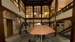 A spacious indoor courtyard with a round table and chairs, a large umbrella, and a staircase. - Hotel Casa Olmedo (Quito)