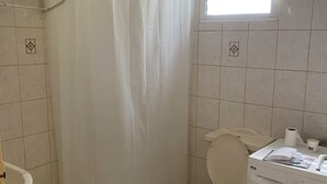 Un bany amb dutxa, vàter i rentamàquines.