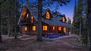 Una cabaña de madera con porche, jacuzzi y una zona de estar al aire libre techada.