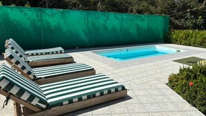 Ett poolområde med solstolar och en liten pool.