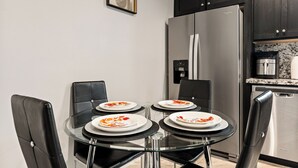 Una cuina moderna amb un frigorífic d'acer inoxidable, una taula de dinar amb quatre caires i una màquina de cafè.