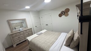Un dormitorio con cama, cómoda, espejo y dos puertas.