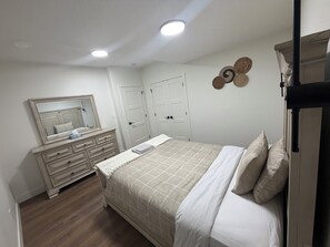 Een slaapkamer met een bed, een dressoir, een spiegel en twee deuren.