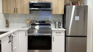 Una cocina moderna con electrodomésticos de acero inoxidable, armarios de madera y una salpicadera de mármol.