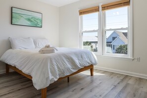 Un dormitorio con cama, ventana y un cuadro en la pared.