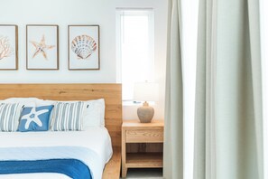 A bedroom with a wooden headboard, a bed with blue bedding, and three framed sea-themed wall art pieces. - Luxury Grace Bay Villa 2/private pool/2 min walk to reef&beach (The Bight Settlement)