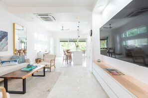 A modern living room with a sofa, coffee table, and a dining area with chairs and a table. - Luxury Grace Bay Villa 2/private pool/2 min walk to reef&beach (The Bight Settlement)