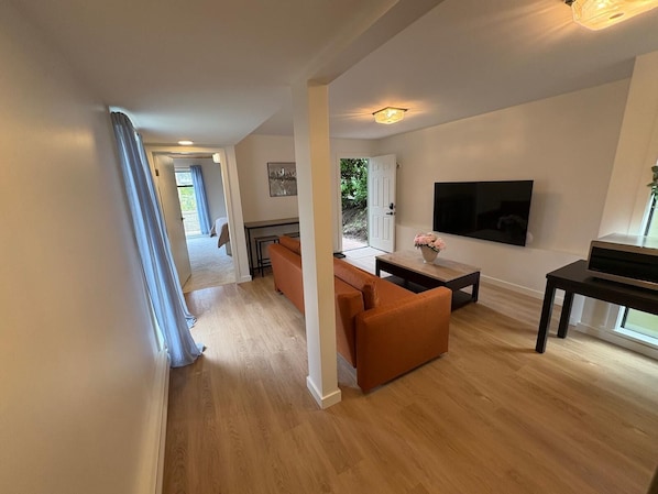 A modern living room with a sofa, coffee table, TV, and a dining area.