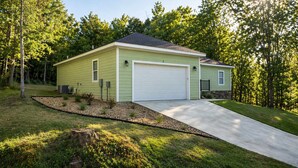 Einbungalow mit Garage, umgeben von einem gepflegten Rasen und Bäumen.