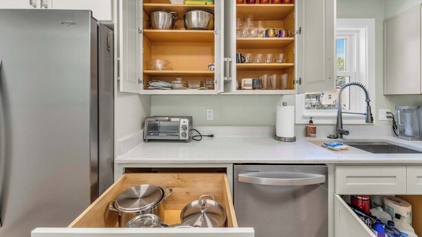 A kitchen with a stainless steel refrigerator, open cabinets with dishes and utensils, a toaster, and a dishwasher. - Great Home_Comfy Beds_Sleeps 8_Hot Tub & Game Room (Kansas City)