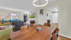 A dining area with a wooden table, chairs, and a ceiling light fixture. - Great Home_Comfy Beds_Sleeps 8_Hot Tub & Game Room (Kansas City)
