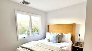 A bedroom with a bed, a window, a bedside table, and a bench. - Pool tennis gym Bikes all included & <2m’s fr/ all (Southampton)
