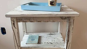 A rustic white wooden table with a blue tray and a vanilla candle. - Pool tennis gym Bikes all included & <2m’s fr/ all (Southampton)