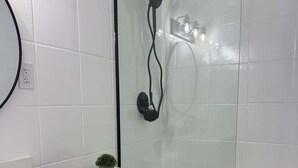 A modern bathroom with a glass-enclosed shower, a white toilet, and a wooden vanity with a mirror. - Pool tennis gym Bikes all included & <2m’s fr/ all (Southampton)