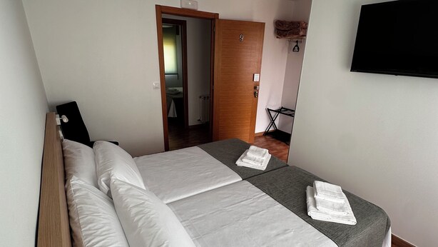 A modern hotel room with a large bed, a flat-screen TV, and a ceiling fan. - Pensión Mirador de Rourís (O Pino)