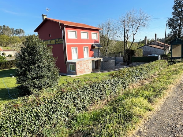 A red two-story house with a visible garage and a small garden area.