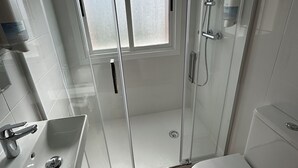 A modern bathroom with a glass shower enclosure, a toilet, and a sink with a faucet. - Pensión Mirador de Rourís (O Pino)