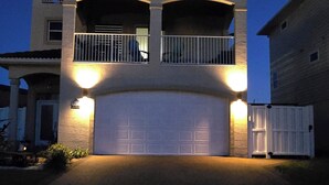 Una casa de dos pisos con garaje, balcón e ingreso bien iluminado.