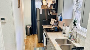 A compact kitchen with a refrigerator, stove, sink, and a small window with curtains. - “Up in the hill” is a charming, 1 bedroom apartment located in Haines City (Haines City)