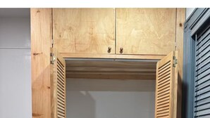 Une armoire en bois avec deux portes, une étagère et une tringle pour suspendre les vêtements.