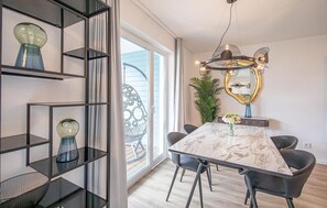 A modern dining area with a marble table, dark chairs, a decorative mirror, and a large window with a view. - Awesome apartment in OstseeResort Olpenitz (OstseeResort Olpenitz)