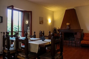 A dining room with a table, chairs, a fireplace, and a sofa.