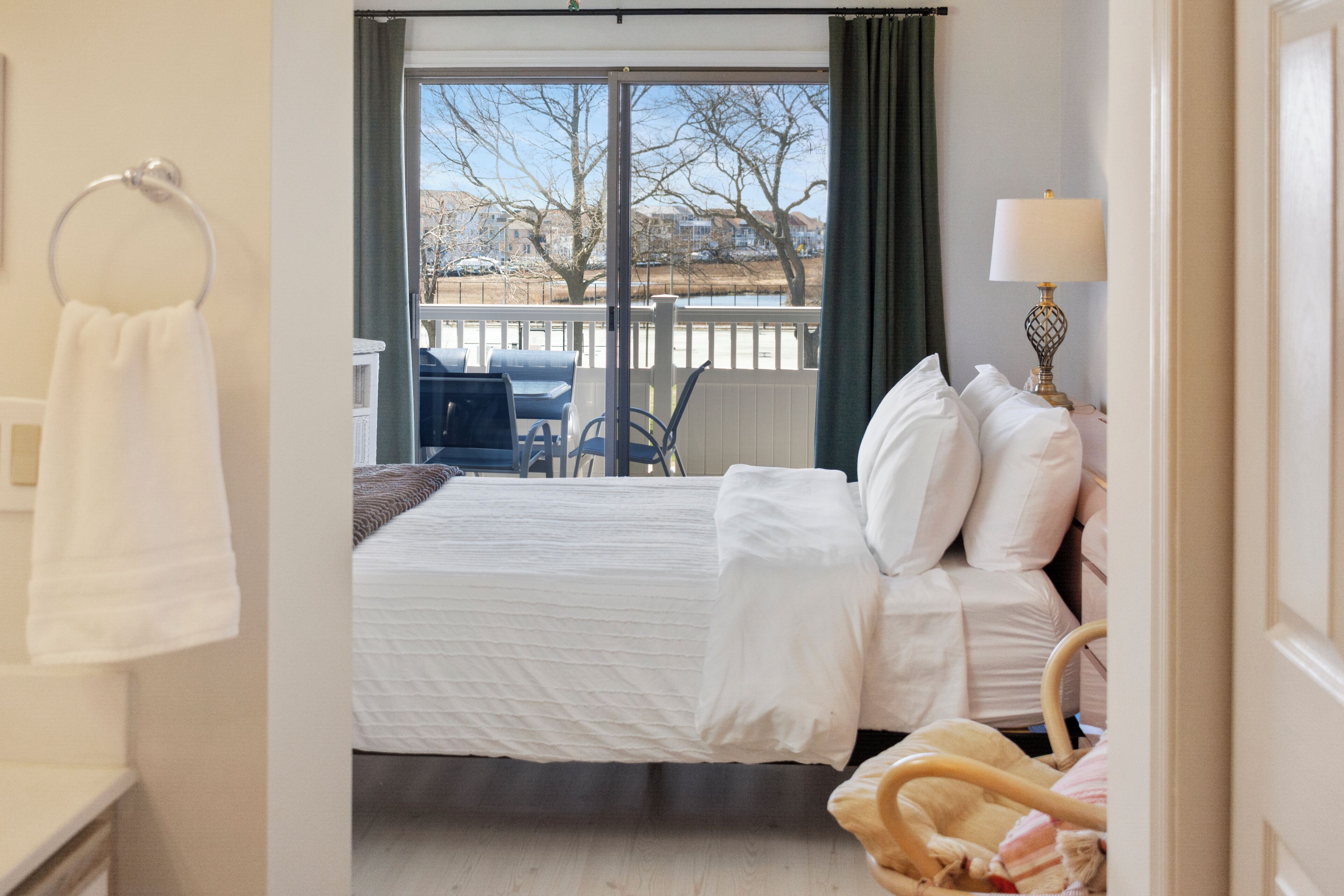 A bedroom with a bed, a chair, a lamp, and a view of a balcony.