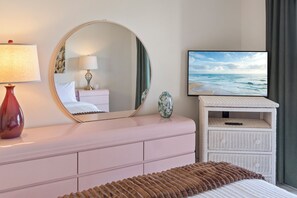Een slaapkamer met een bed, een televisie, een spiegel, een dressoir en een nachtkastje.
