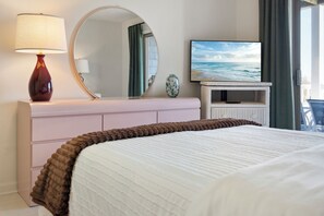 Ein Hotelzimmer mit Bett, Fernseher, Spiegel, Lampe und Meerblick.