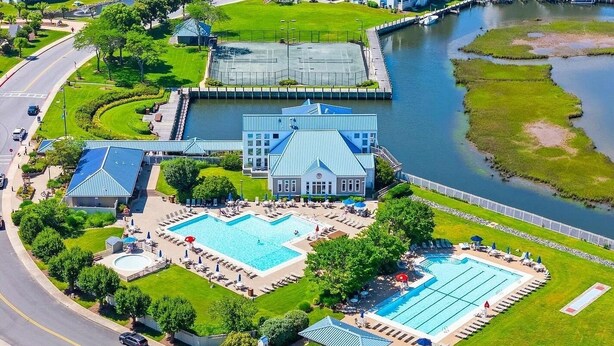 Un hotel grande con piscina, cancha de tenis y vista al río.