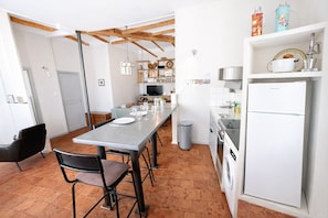 Una cocina moderna con comedor, que incluye una mesa larga, sillas, horno empotrado y refrigerador.
