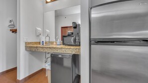 A kitchenette with a stainless steel refrigerator, a microwave, a sink with soap dispenser, and a dish drying rack. - High Tides - Sleeps 14 | Video Games (Wisconsin Dells)